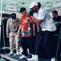 a group of people standing on stage in front of a tent